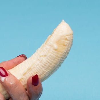 person holding a banana with cream on top