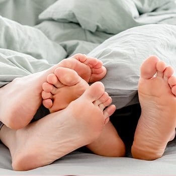 couple feet cuddling under sheets
