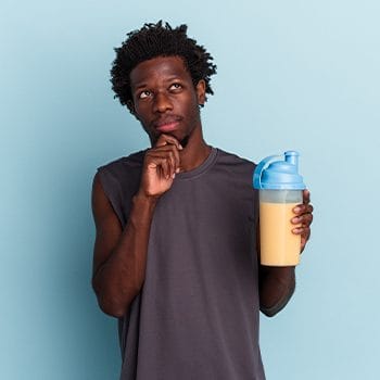 man contemplating while holding a protein drink