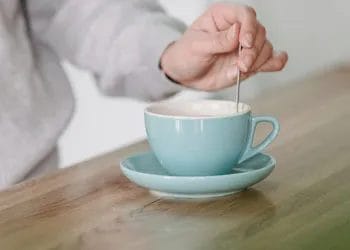 woman using a spoon to mix a mug drink