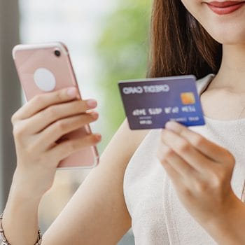 woman holding both her phone and credit card