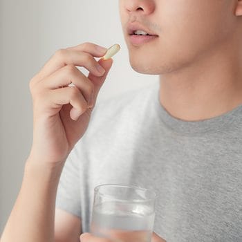 man drinking a capsule supplement