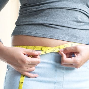 person using a measuring tape on waistline