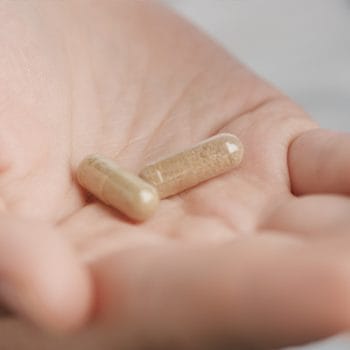 hand view of a person with two supplement capsules