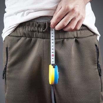man using a tape measure on his crouch