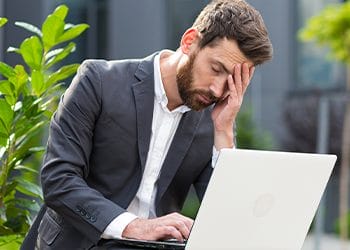 man with his hands on his face upset while working
