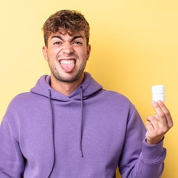 man holding up medicine in disgust
