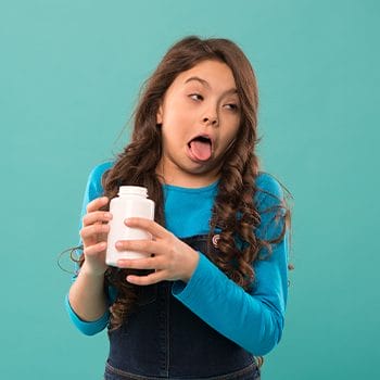 little girl holding a container with a disgusted face