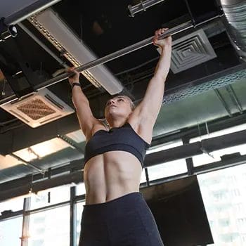woman using a pull up bar inside a gym