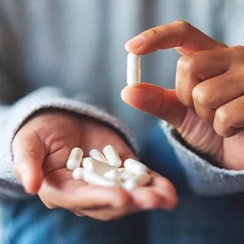 person holding up one pill from a stack of it