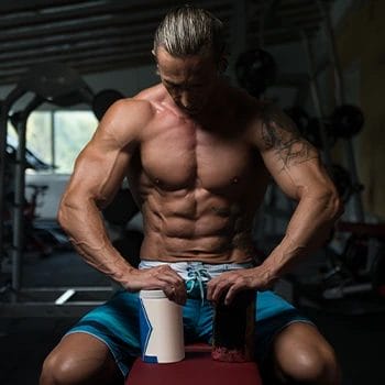 man looking at supplement while seated at the gym