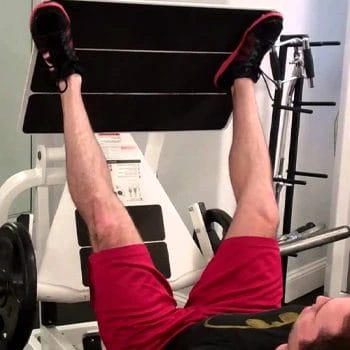 man in a wide stance using a leg press machine