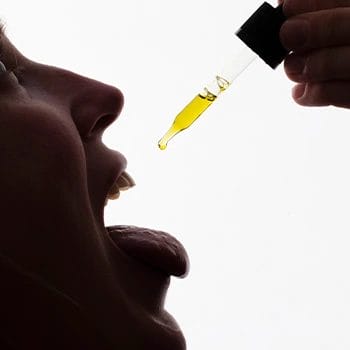 mouth view of a woman using medicine drops