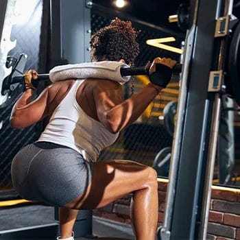 woman working out her squats with a barbell at the gym