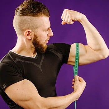 man using a tape measure on his biceps