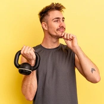 man holding up a kettlebell and thinking
