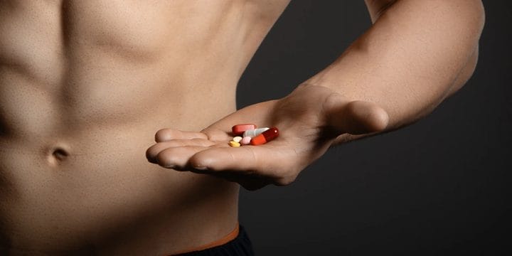 Muscular person holding pills
