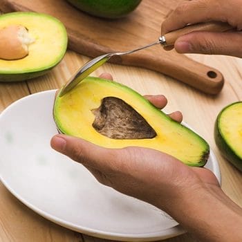 Eating a slice of avocado using a spoon