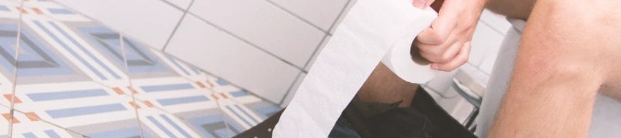 A man holding a toilet paper roll while sitting on the toilet