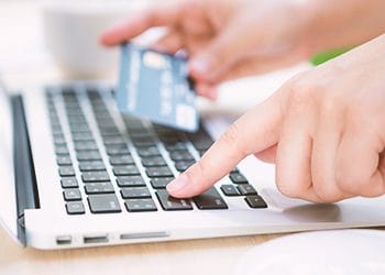 A man using the laptop while holding a credit card