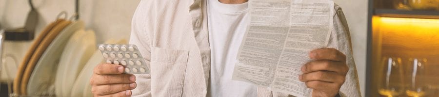 A man holding pills and looking at ingredients