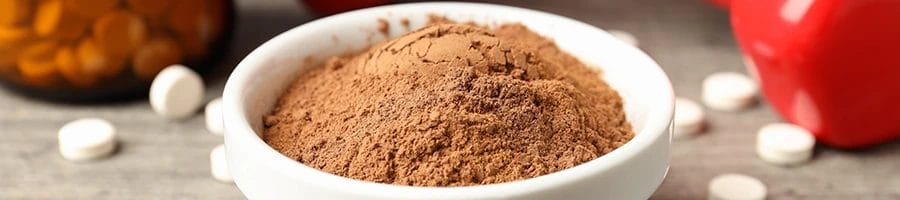 Close up image of supplement powder with pills in the background