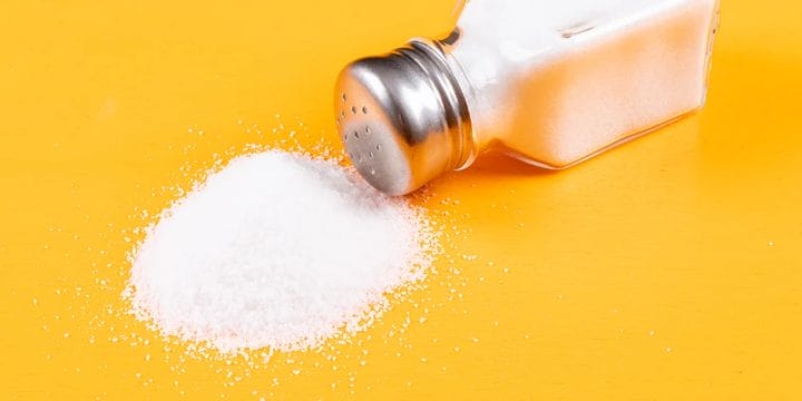 Spilled salt on yellow background