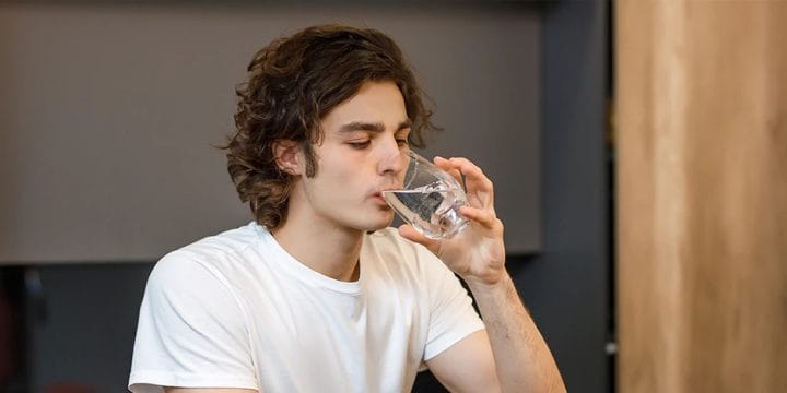 A person drinking water in the kitchen