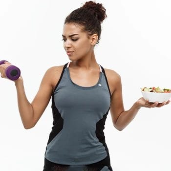 A woman holding a dumbbell and a bowl of meal