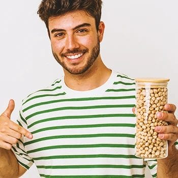 A person holding up beans in a jar