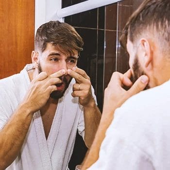 A person looking at his face in the mirror