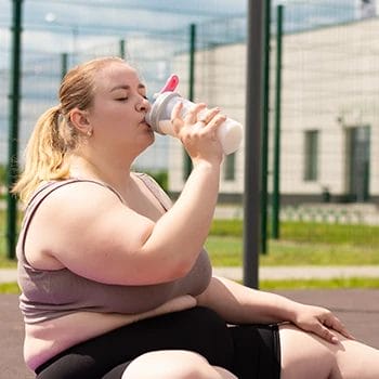 A woman drinking protein shake outdoors