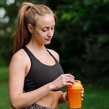 A tired woman holding a supplement drink