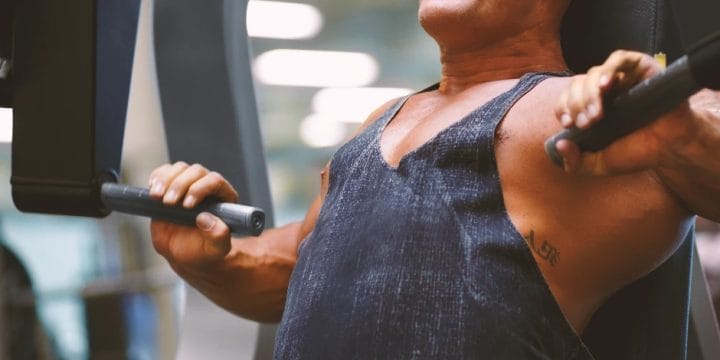 A muscular person lifting weights while using naked mass protein powder