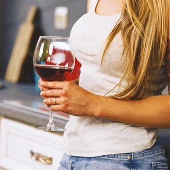 Close up shot of a woman holding wine in a kitchen
