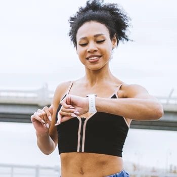 A person jogging outside while looking at her smart watch