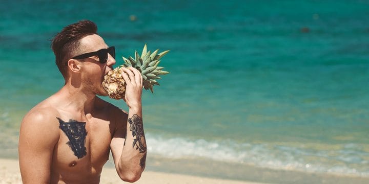 A person eating a pineapple at the beach