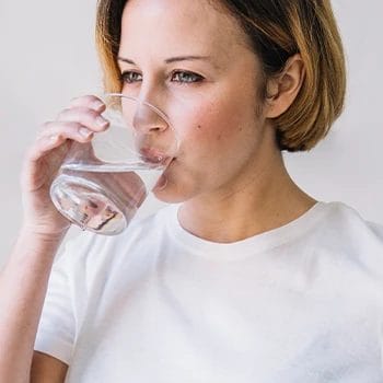 A woman drinking a glass of water before bed