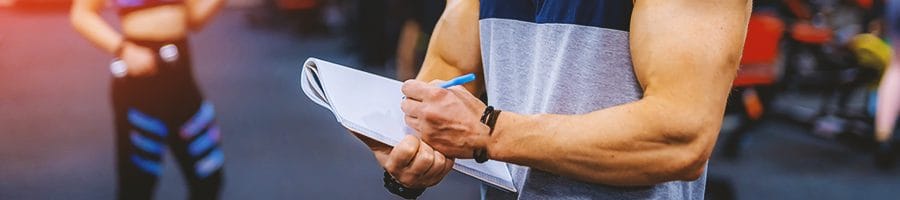 A buff gym coach taking down notes