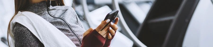 A teenager in the gym looking at her phone