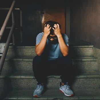A stressed man sitting down on the stairs