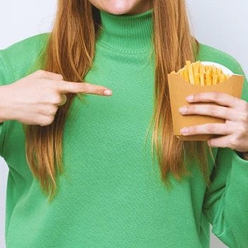 A person holding cooked potato fries
