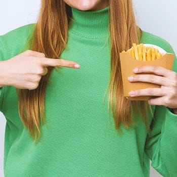 A person holding cooked potato fries