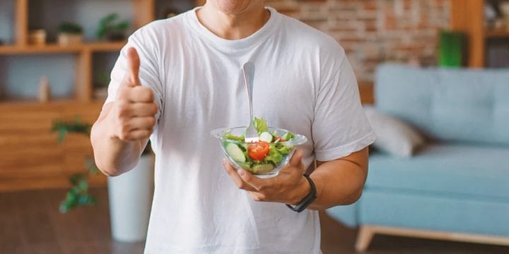 A fit male holding a bowl of salad