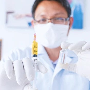 A doctor holding a bottle and syringe of steroids