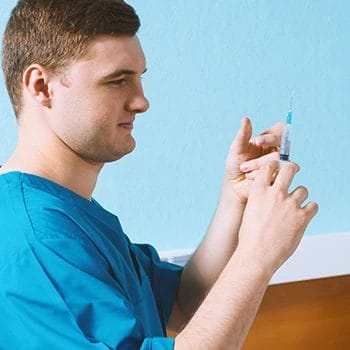 A man holding a syringe at home
