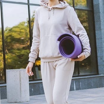 A woman walking outside with a yoga mat