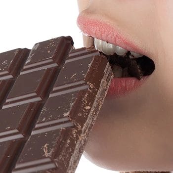 Woman biting chocolate bar up close