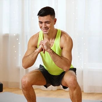 Man doing squats inside his home