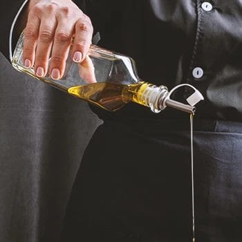A person pouring down olive oil